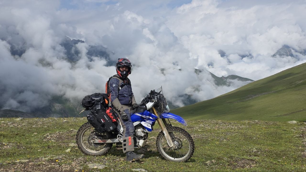 Rider on a Yamaha with GREATRIP luggage on a green mountain slope among the clouds